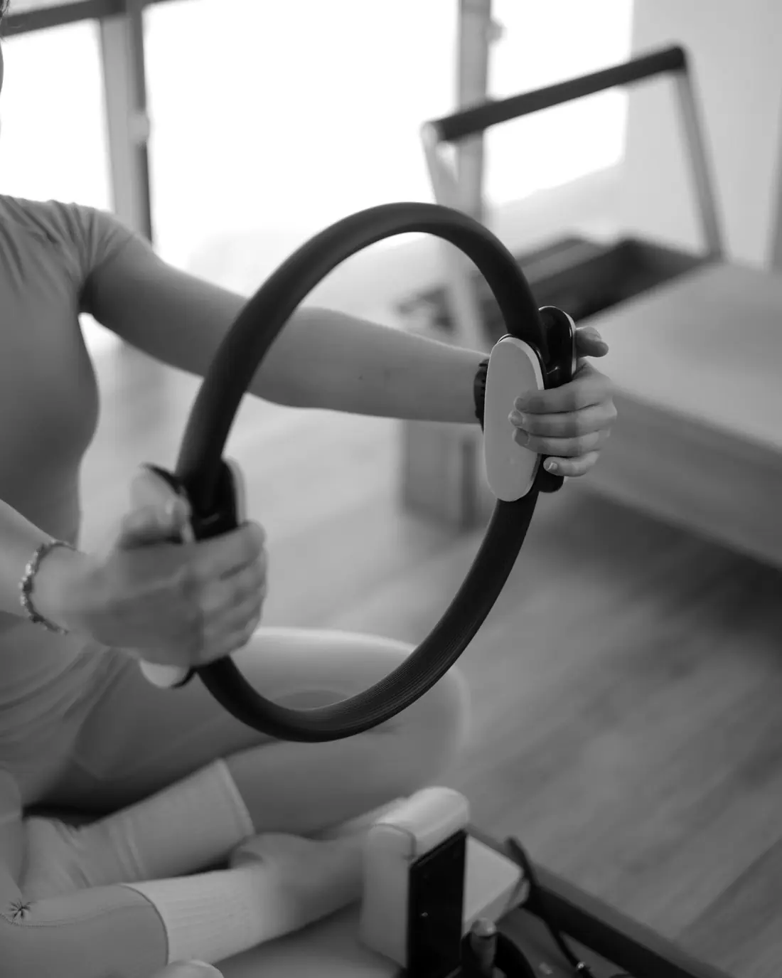 Hands pressing a Pilates ring during a mat class